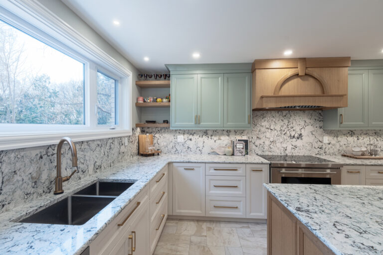 Kitchen with white and green cabinets, gold hardware and real woof island and rangehood, cream coloured slate tile.