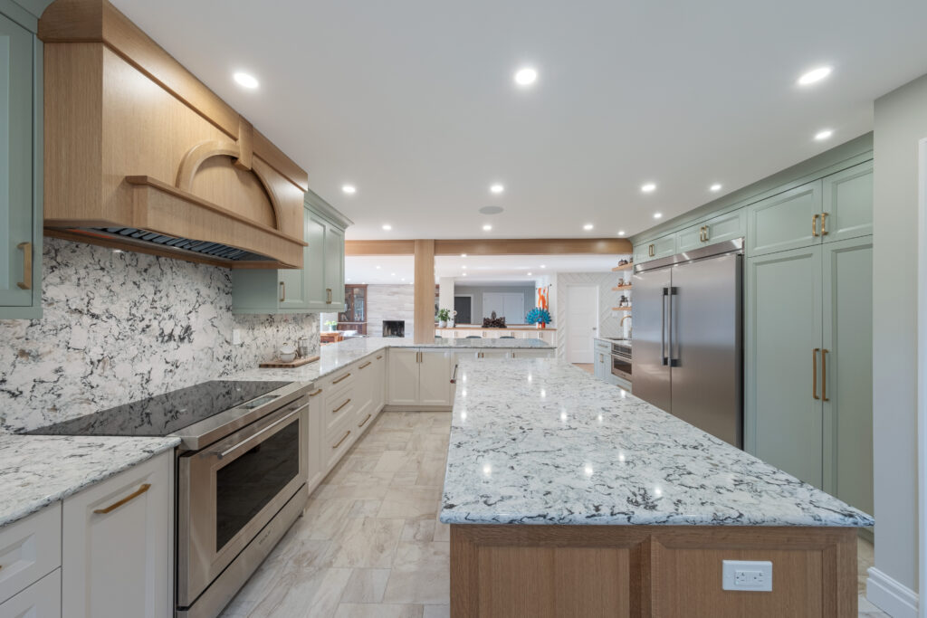 Kitchen with white and green cabinets, gold hardware and real woof island and rangehood, cream coloured slate tile.